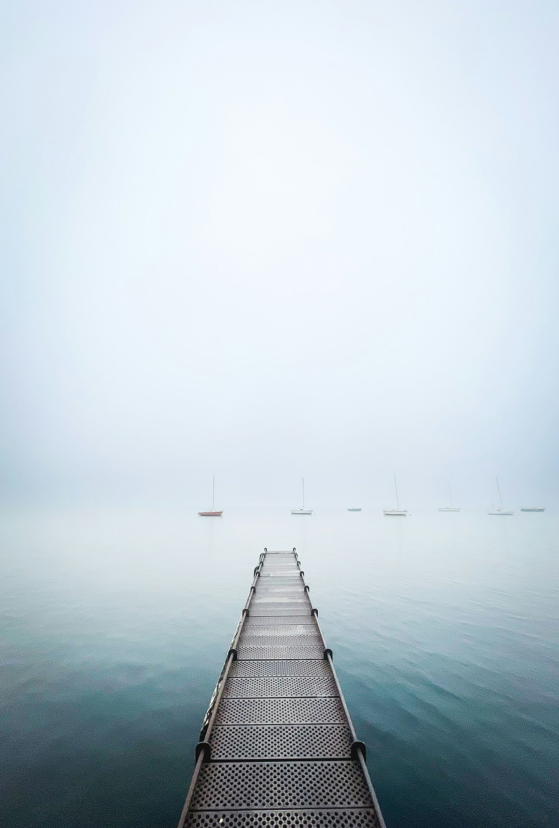 Long ponton qui s'avance dans un lac sous la brume du matin