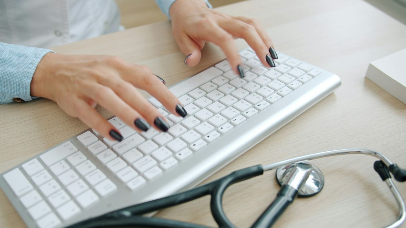 Stéthoscope posé à côté d'un clavier d'ordinateur blanc sur un bureau